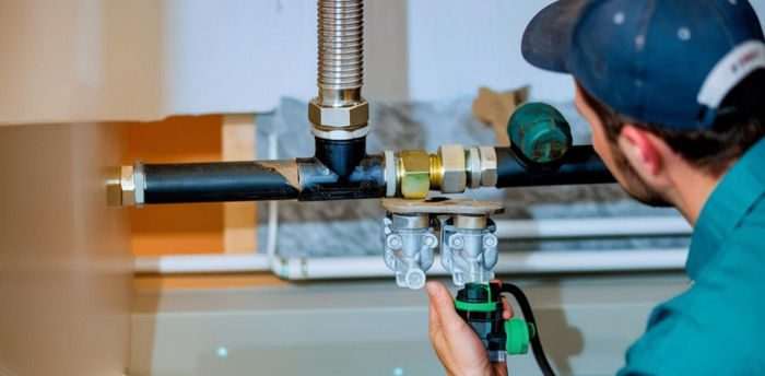 Plumber inspecting gas line connections with valves and fittings in a residential setting, emphasizing reliable gas line services and maintenance.